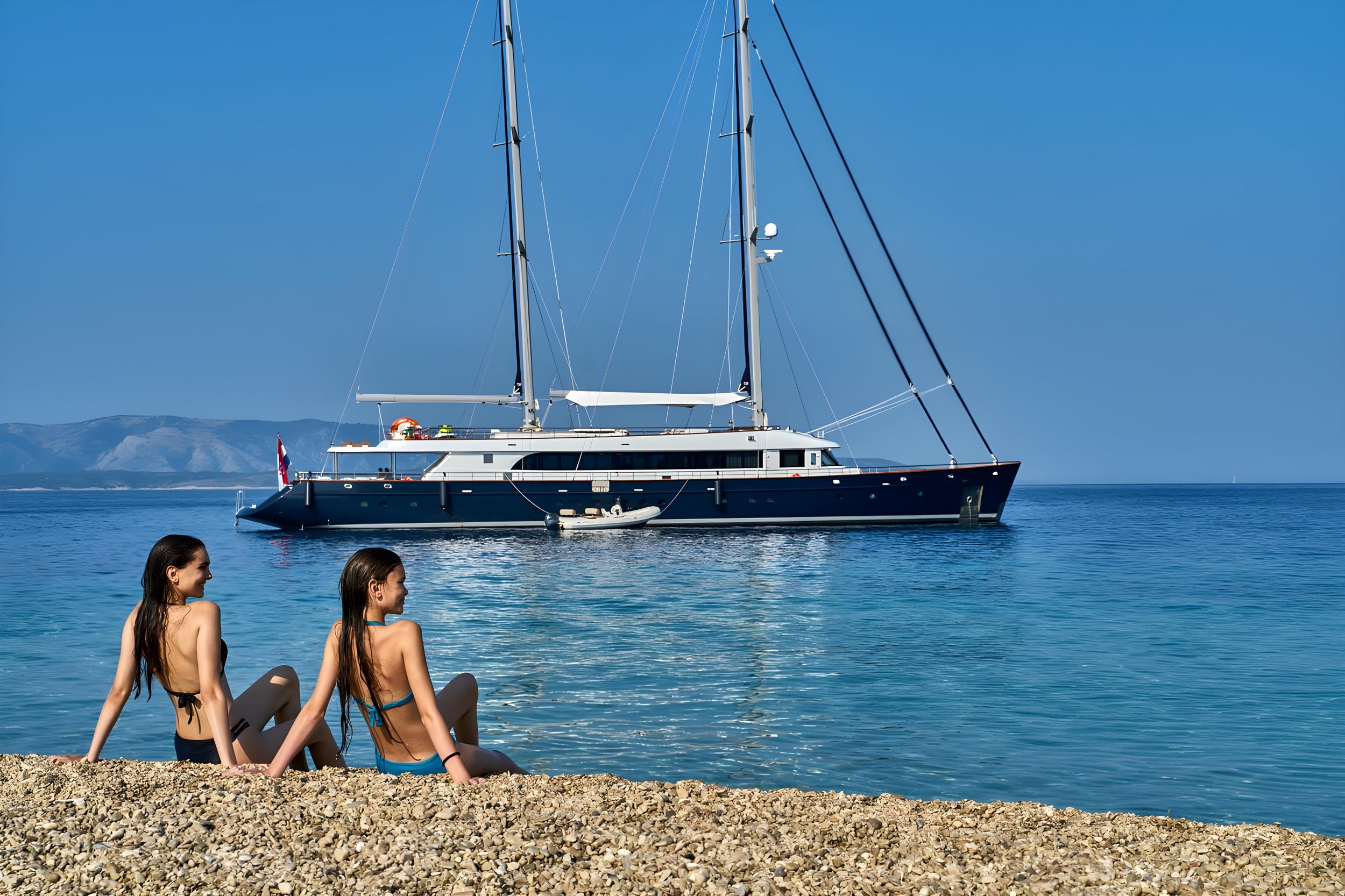 Dark blue luxury sailing yacht anchored in crystal clear Mediterranean waters