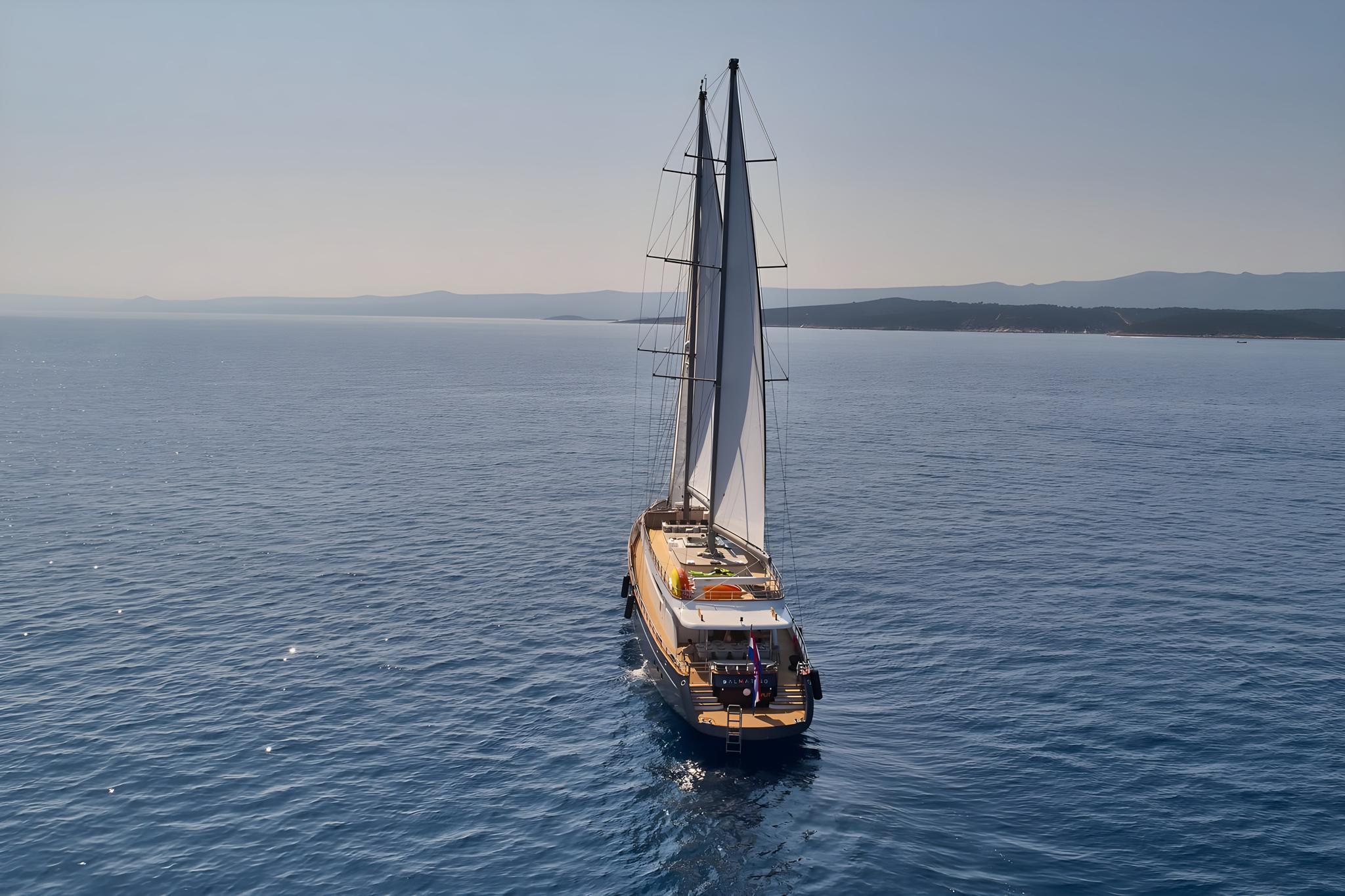 Aerial view of luxury sailing yacht with white sails on blue water