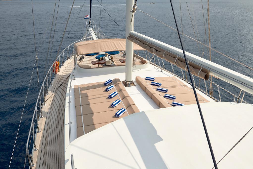 luxury sailing yacht forward deck with teak flooring and cushioned seating areas