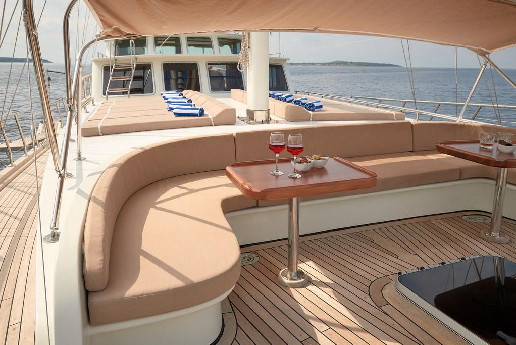 luxury yacht aft deck curved seating area with wine glasses on wooden table