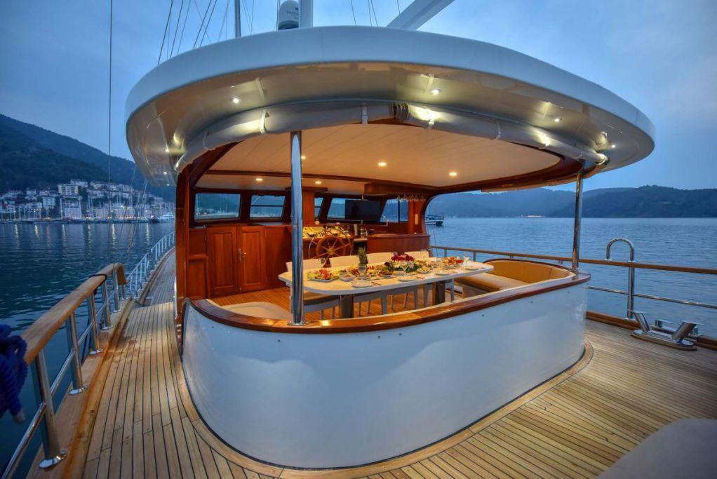 luxury yacht aft deck with covered dining area and set table at twilight