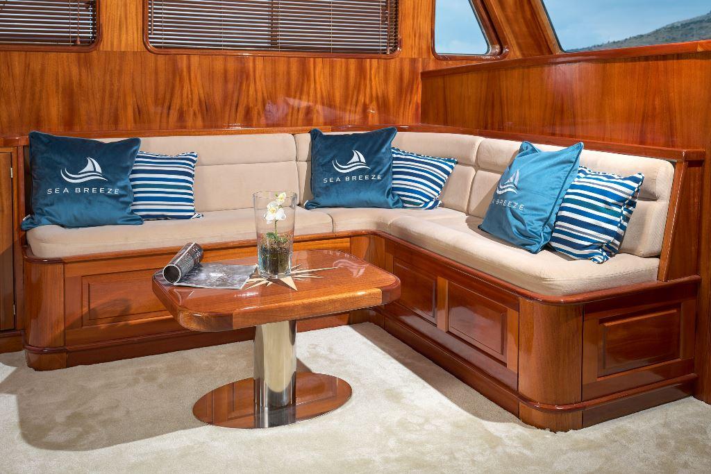 Luxury yacht salon with L-shaped seating, wooden paneling and coffee table