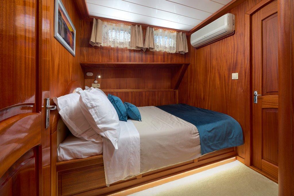 luxury yacht cabin interior with double bed white linens wood paneling