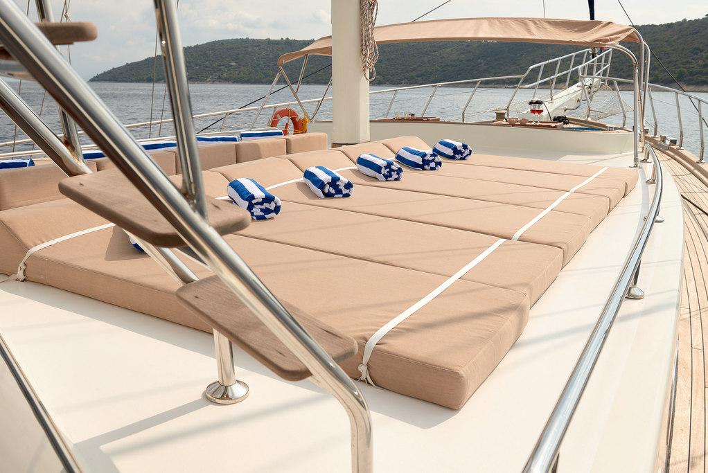luxury yacht sun deck featuring large sunbathing pad with blue striped towels