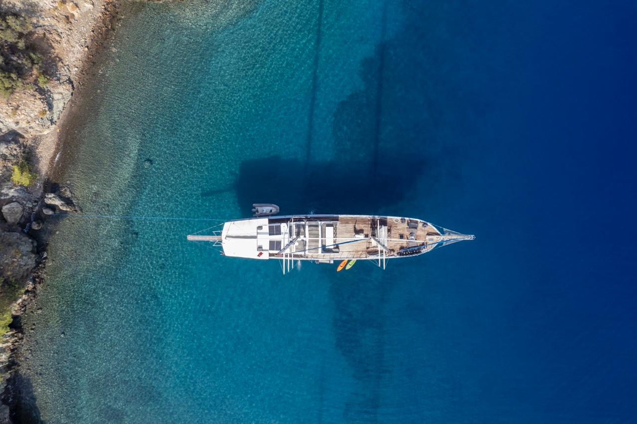 aerial view of white gulet yacht anchored in crystal clear turquoise Mediterranean bay