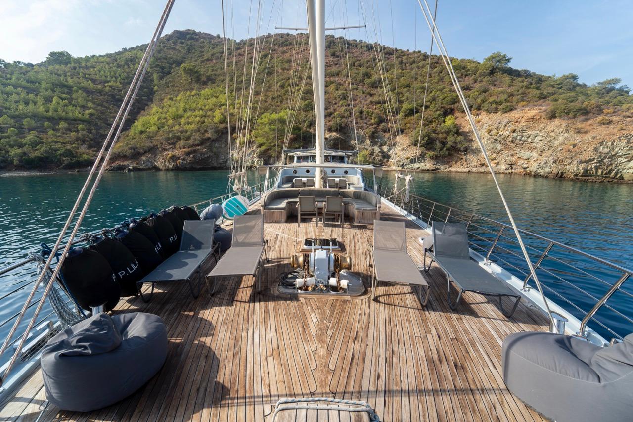 gulet aft deck with curved seating, teak planking and rigging visible