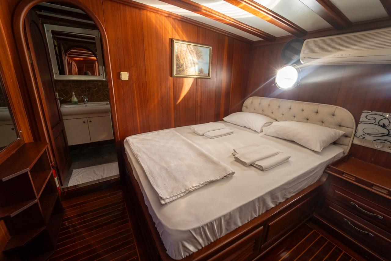 yacht guest cabin featuring double bed with white linens and en-suite bathroom with vanity