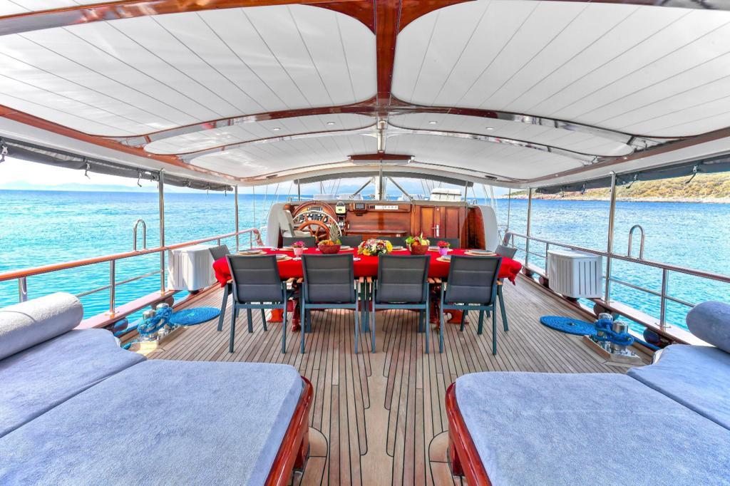 yacht aft deck with outdoor dining table, seating, and swimming platform with water toys