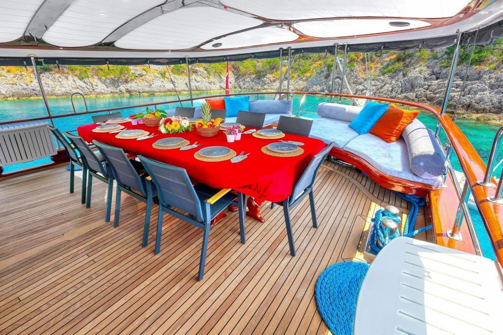 luxury yacht aft deck dining area with red tablecloth and curved seating in turquoise bay