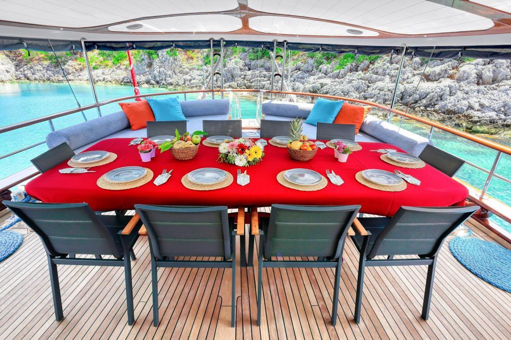 yacht aft deck dining table with red tablecloth, place settings, and fresh fruit baskets