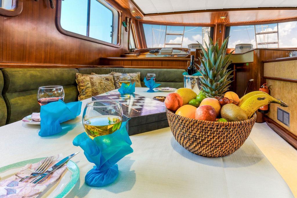 yacht dining table with wicker fruit basket, wine glasses and blue napkins