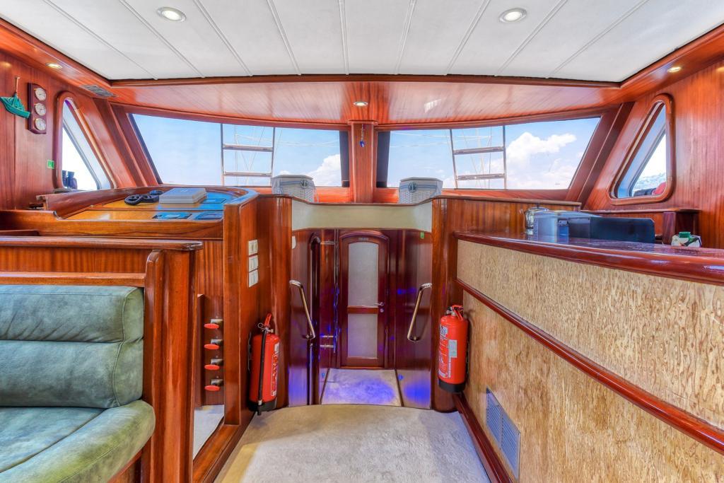 yacht salon with curved green seating, rich wood paneling and panoramic windows
