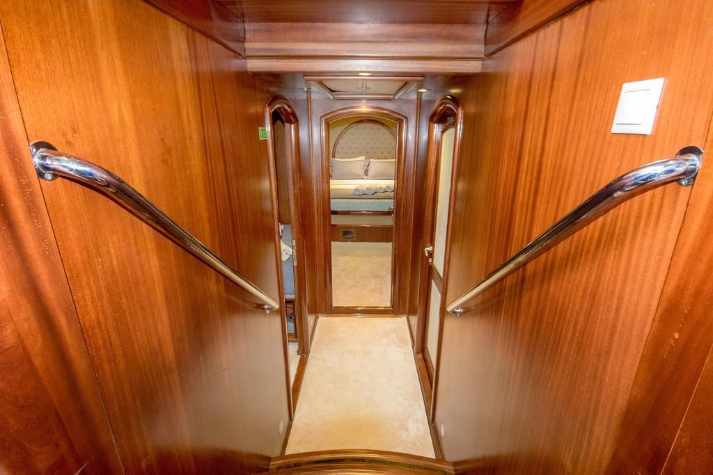 yacht interior staircase with steel handrails and wood paneling leading to cabin