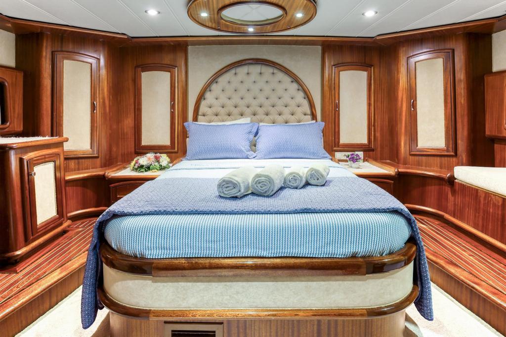 yacht master cabin featuring tufted cream leather headboard, blue bedding and polished wood paneling