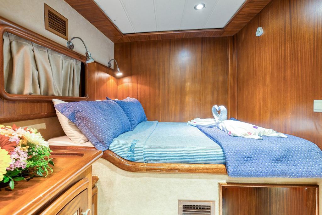 yacht guest cabin featuring double bed with blue textured bedding and wood paneling