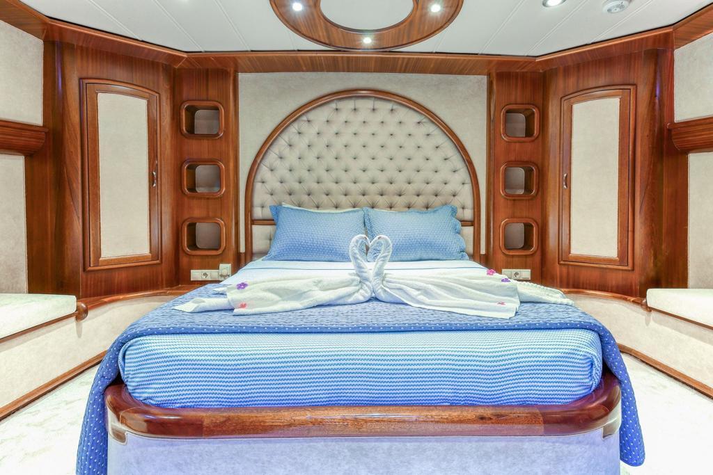 Master cabin featuring diamond-tufted headboard, blue striped bedding, and rich wood paneling
