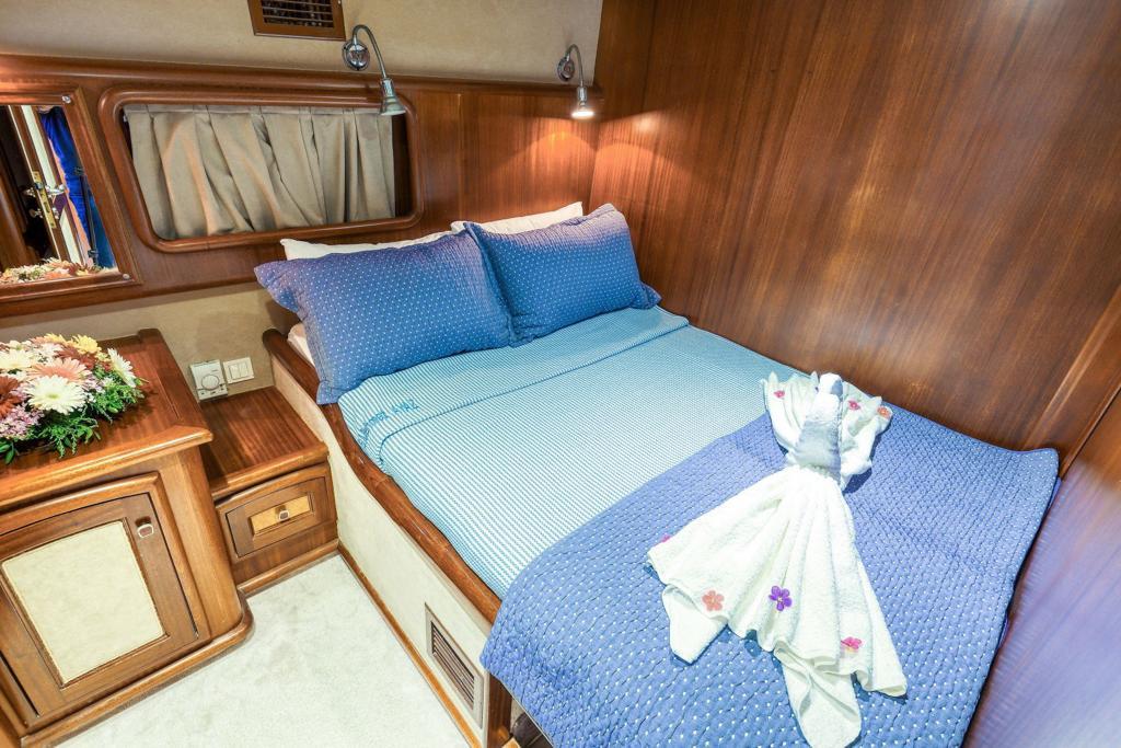 yacht guest cabin featuring double bed with blue striped bedding and wooden interior