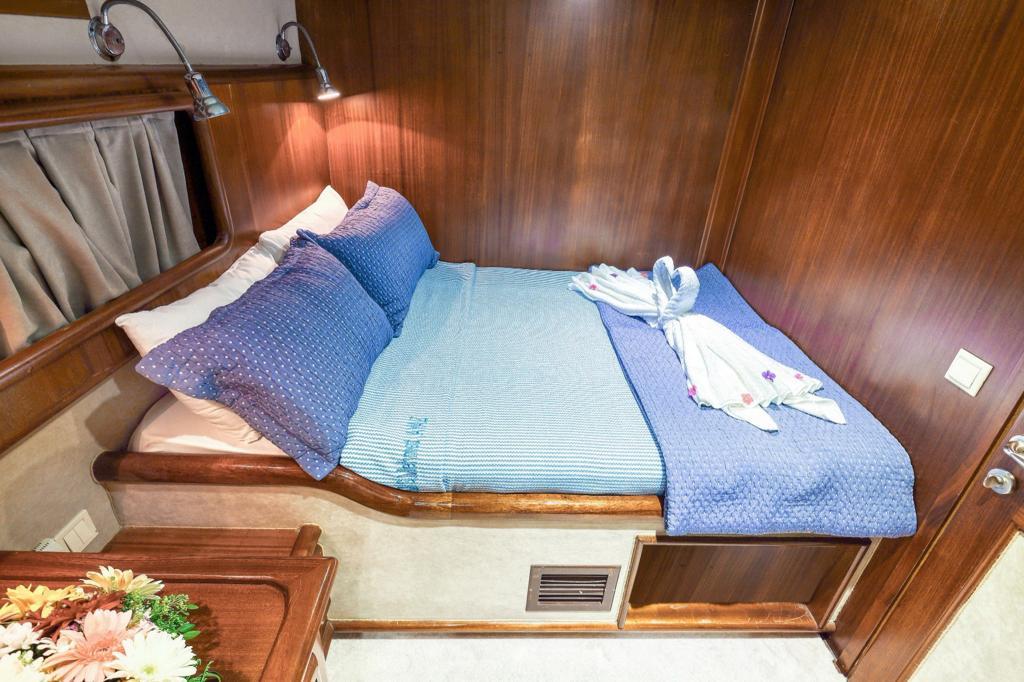 yacht guest cabin featuring double bed with blue striped bedding and reading lights