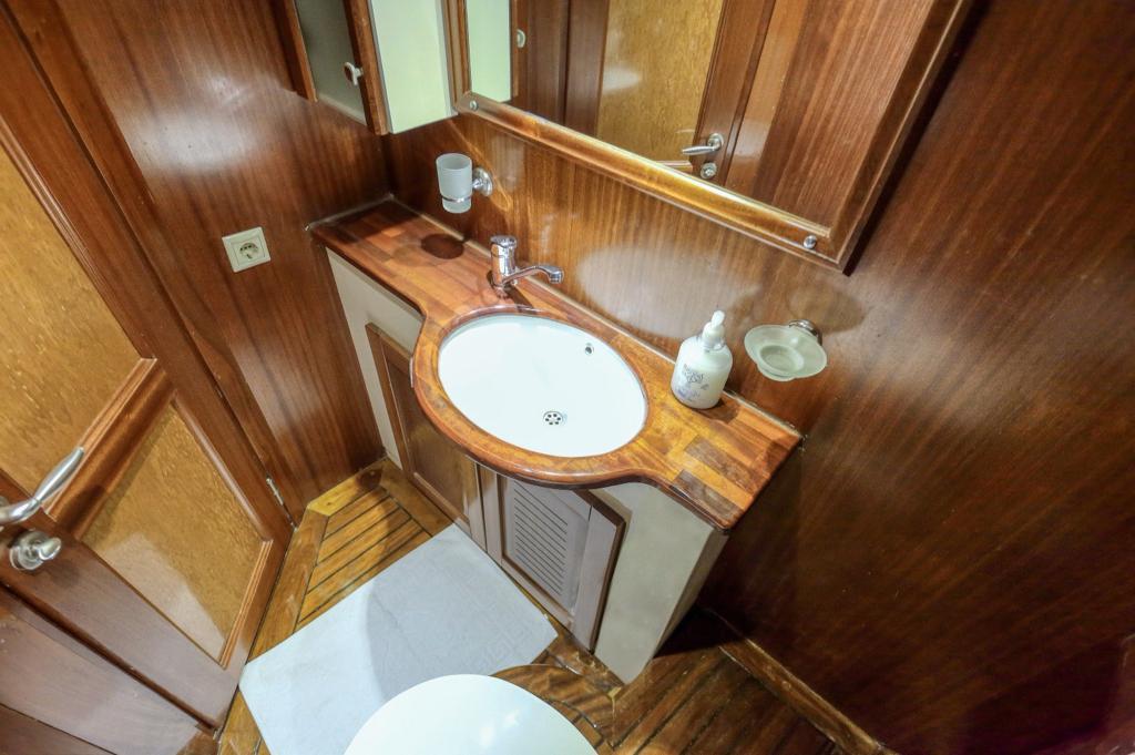 yacht bathroom featuring wooden vanity unit with white ceramic basin and mirror