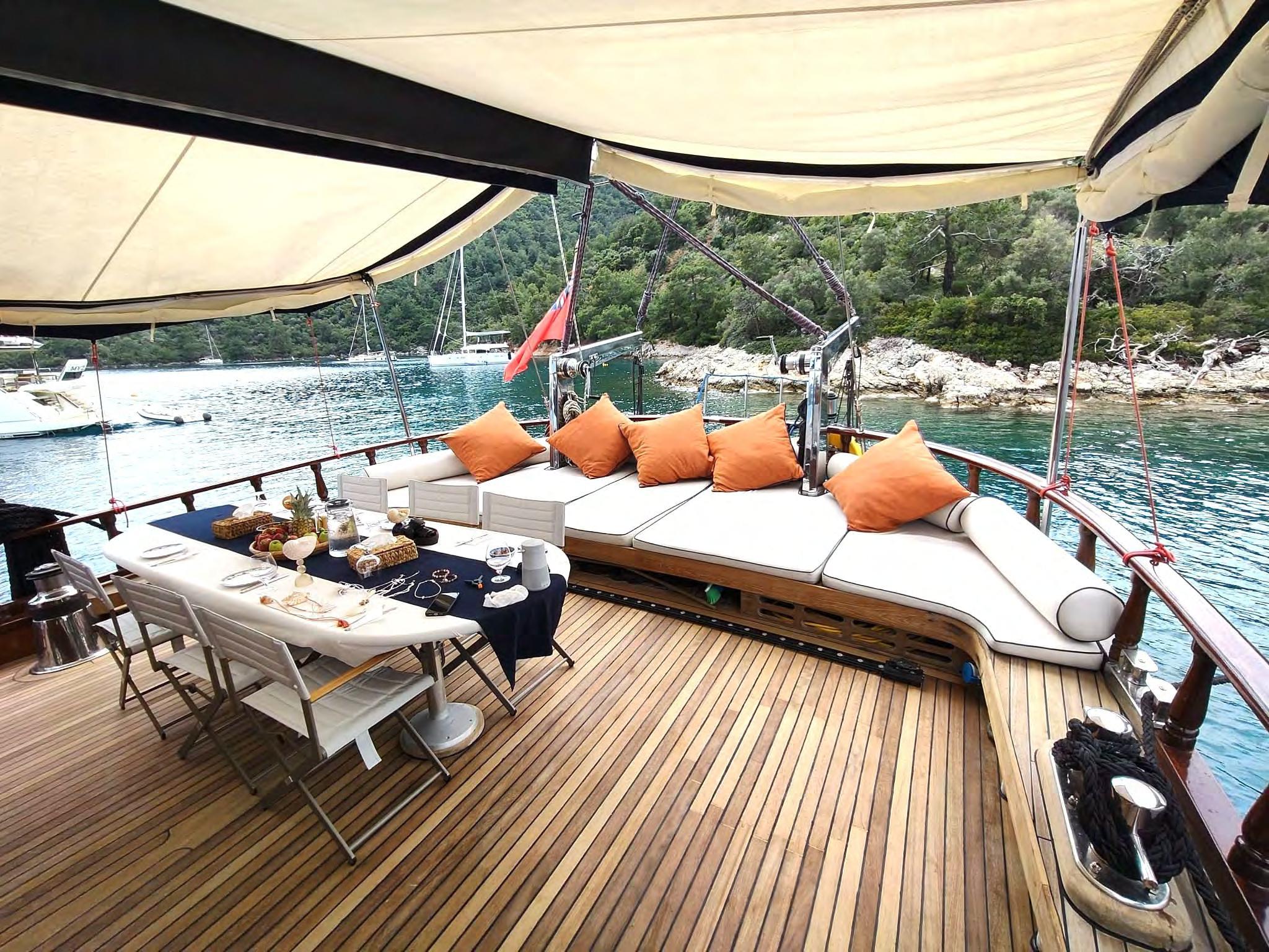 Gulet aft deck dining table with navy cloth, fruit, glasses and place settings under cream awning
