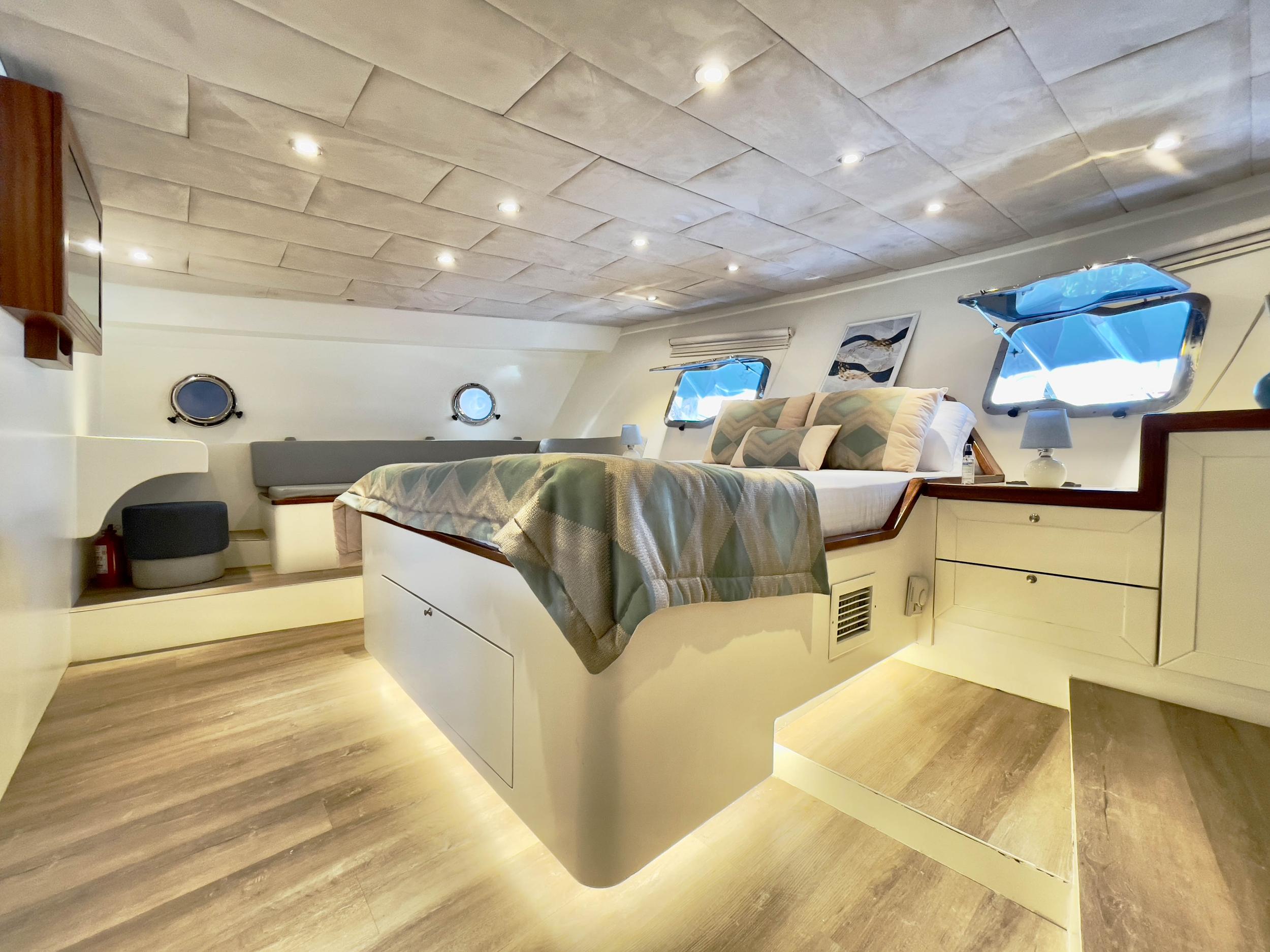 Gulet master cabin with raised king bed, ambient under-bed lighting, portholes and built-in seating