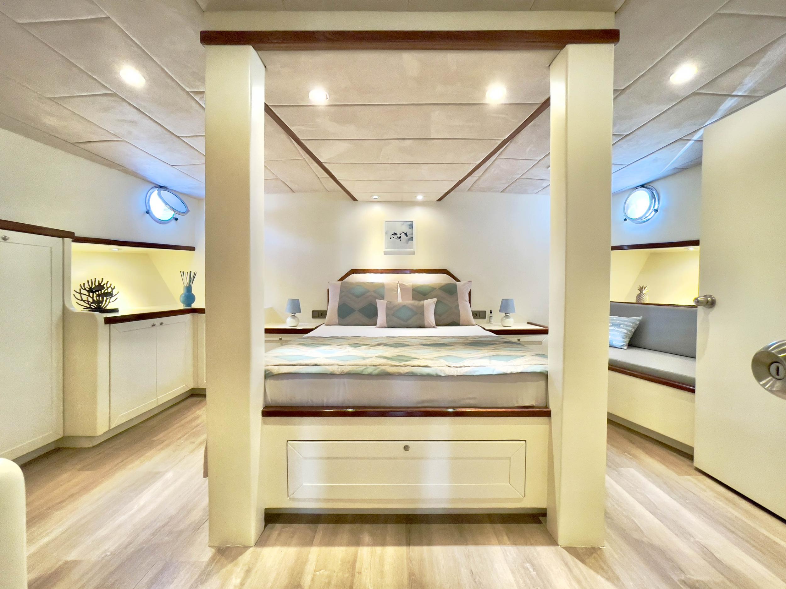 Luxury master cabin with four-poster king bed, built-in storage, twin portholes and seating area