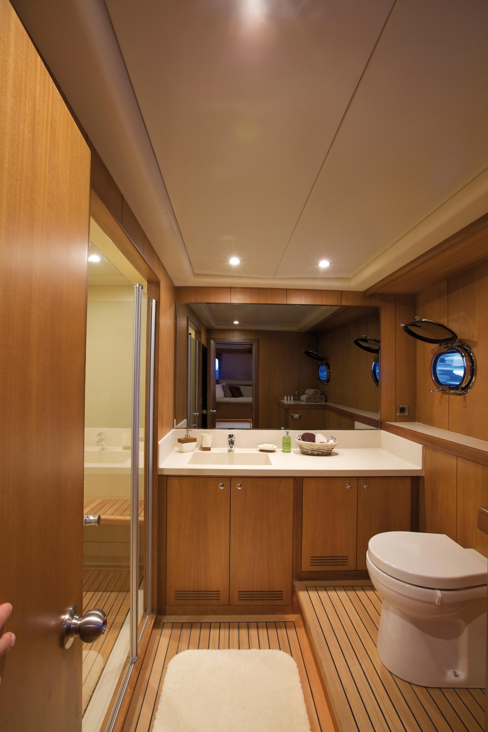 yacht bathroom interior with white vanity sink, wooden cabinetry and teak flooring