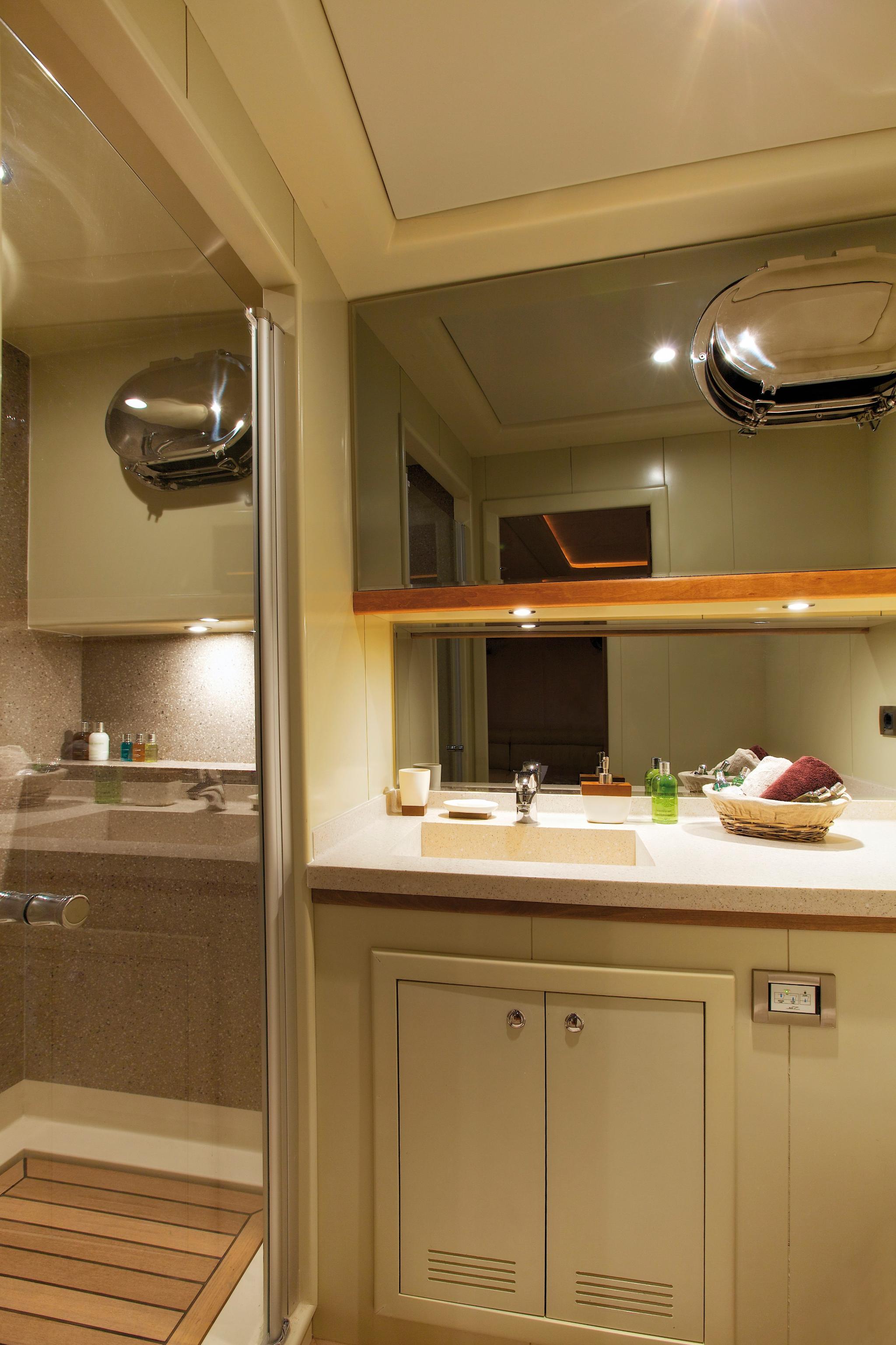 yacht bathroom featuring white vanity with integrated sink, mirror, and glass shower enclosure