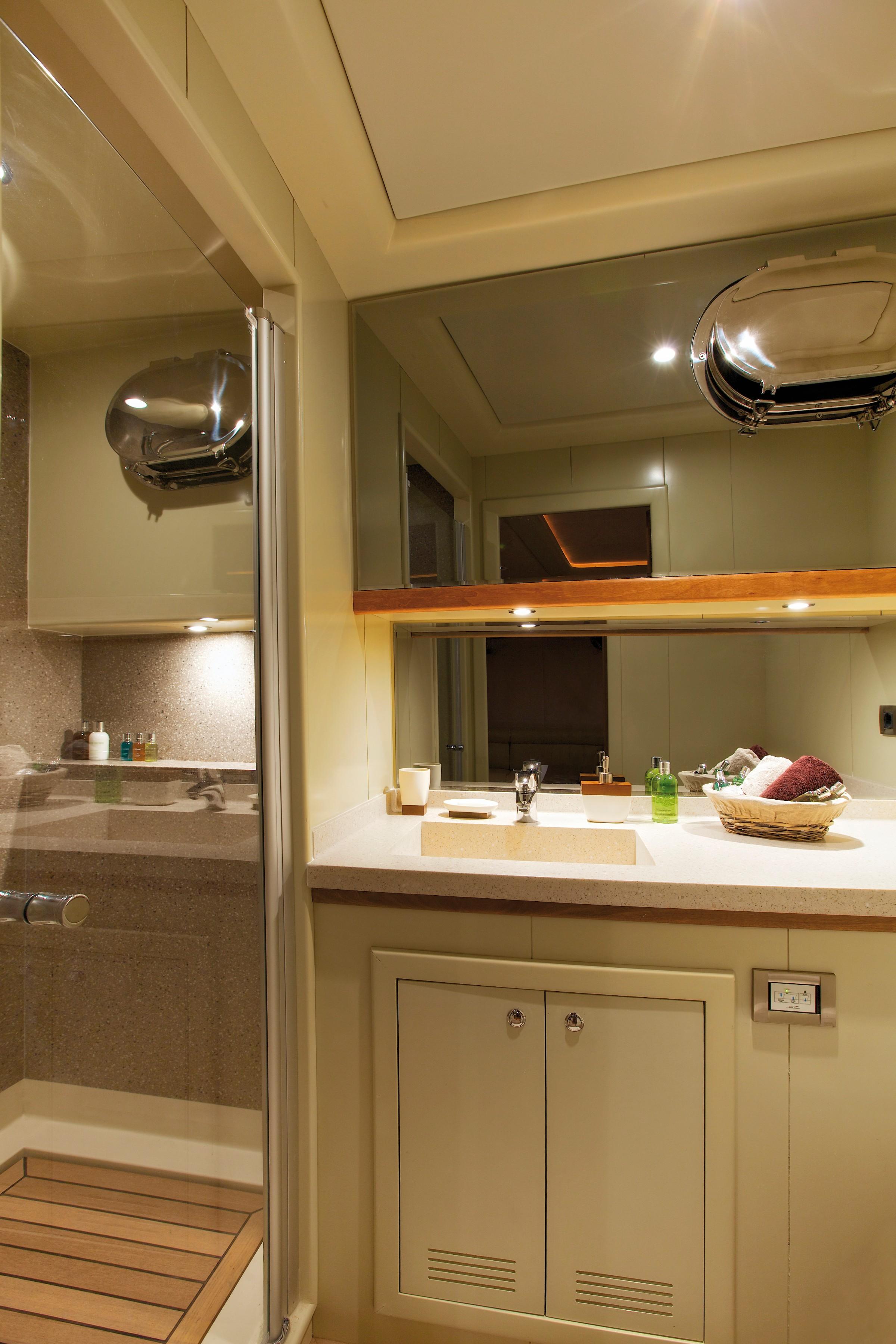yacht bathroom featuring white vanity with integrated sink, mirror, and glass shower enclosure