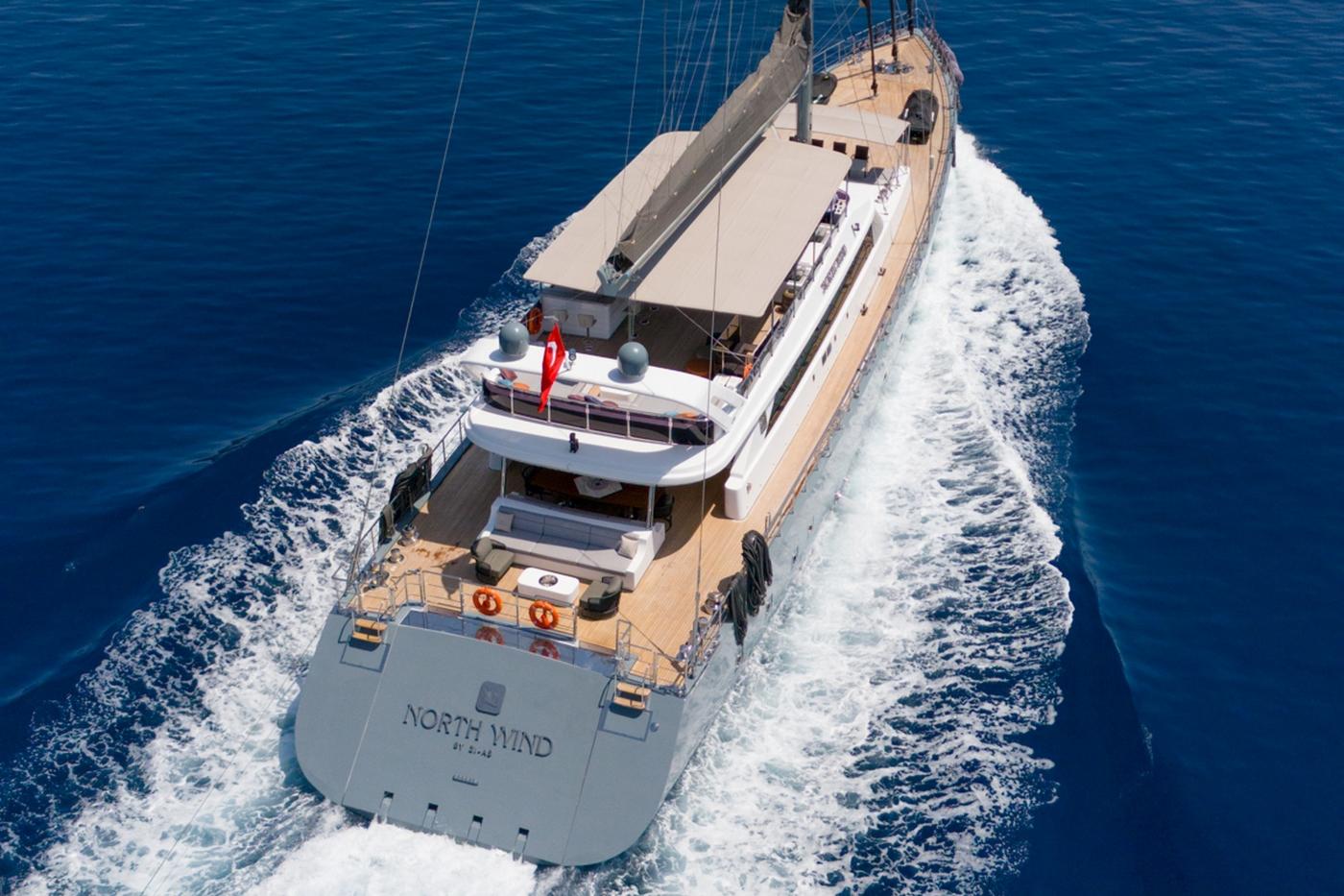 aerial view of North Wind sailing yacht underway with white wake trail in deep blue water