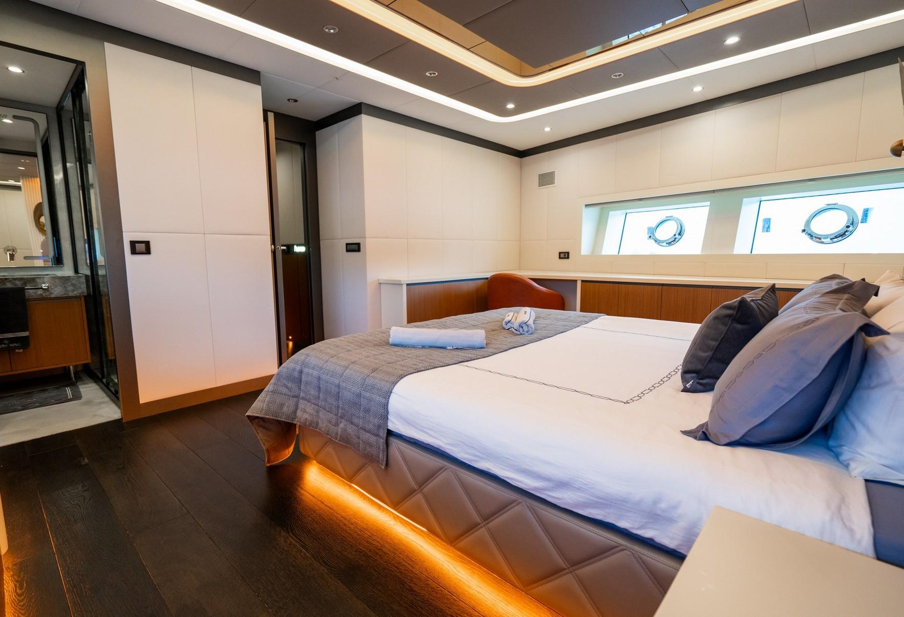 luxury yacht cabin featuring double bed with white linens, wood paneling, and adjacent en-suite bathroom