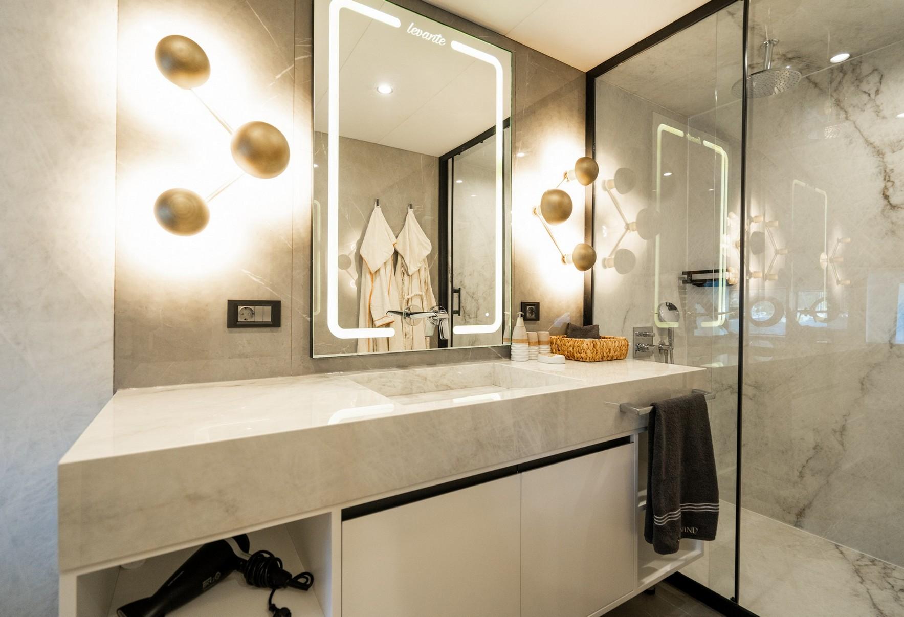 luxury yacht bathroom featuring marble vanity, LED-lit mirror, and glass shower enclosure