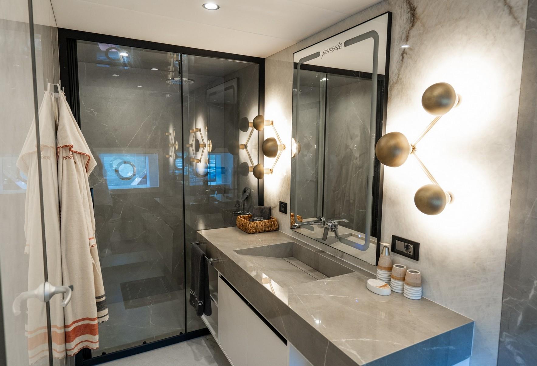 luxury yacht bathroom featuring marble vanity, integrated sink, glass shower enclosure and modern fixtures