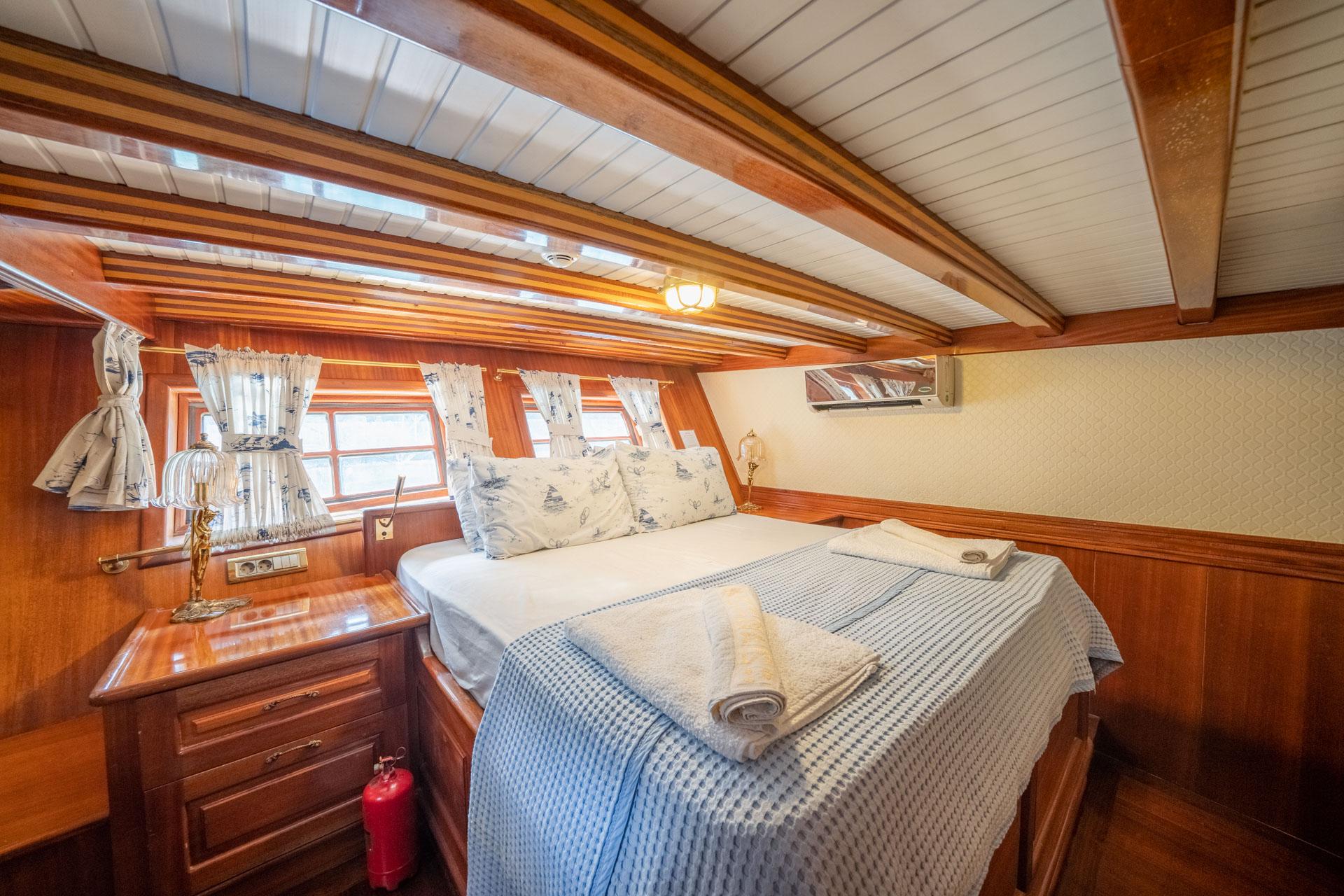 yacht guest cabin featuring double bed with blue checkered bedding and nautical curtains