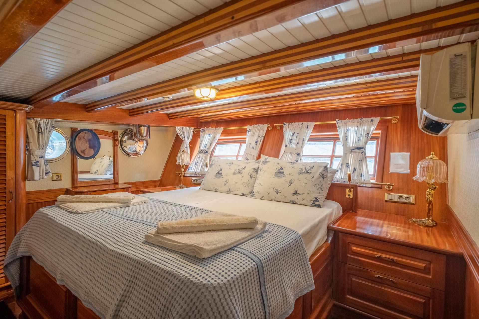 yacht guest cabin featuring double bed with nautical pillows and multiple portholes