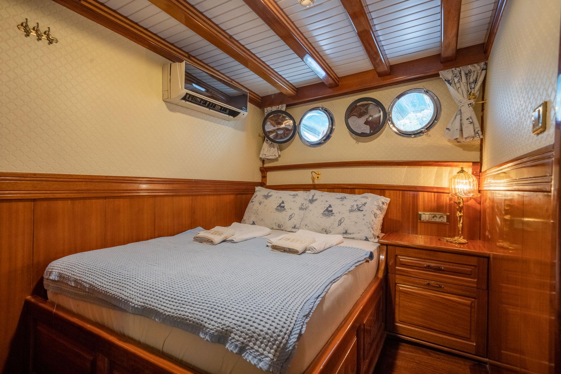 yacht guest cabin featuring double bed with nautical bedding and four round portholes