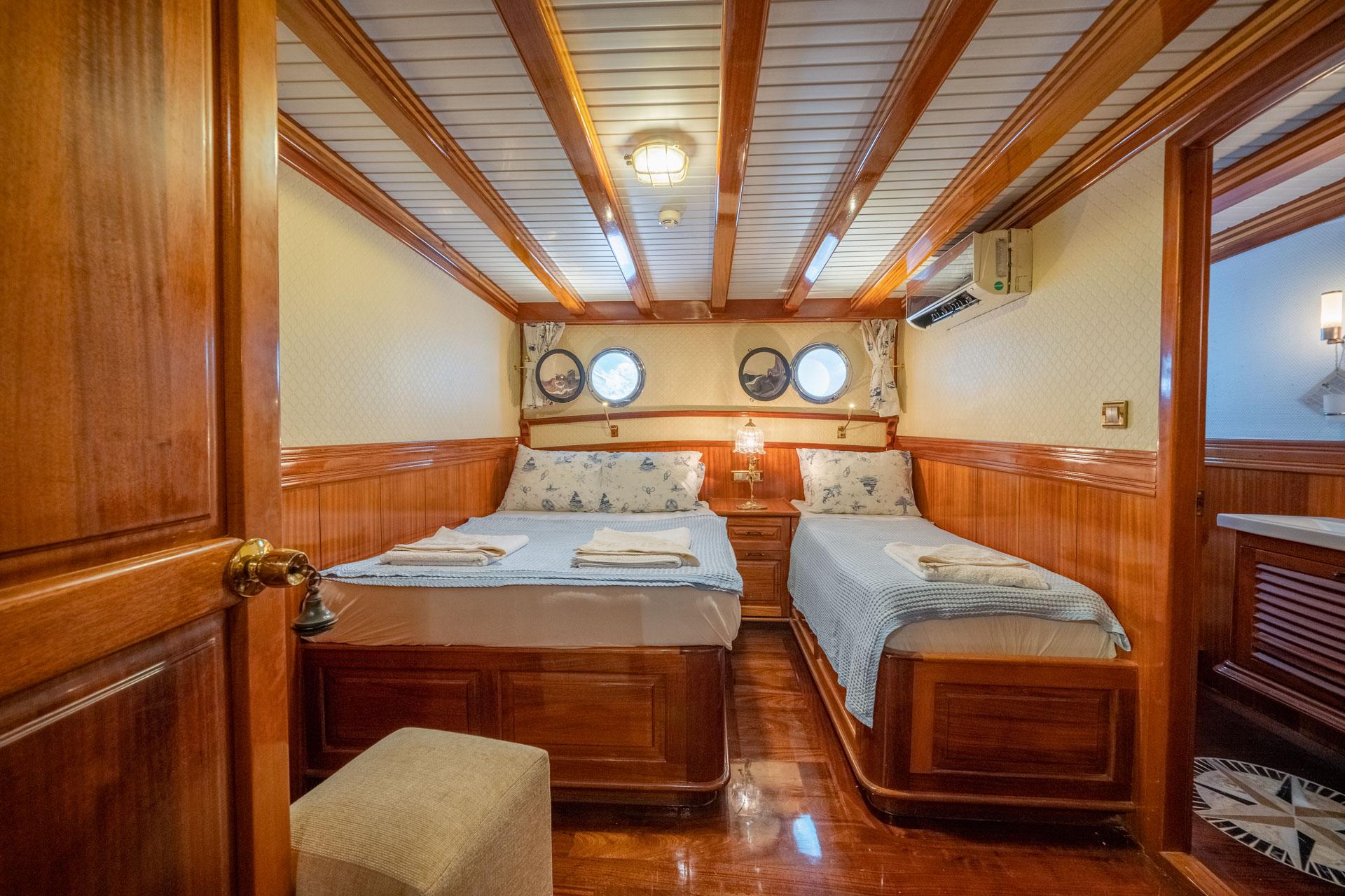 guest cabin featuring twin beds, wooden paneling, four portholes, and built-in storage