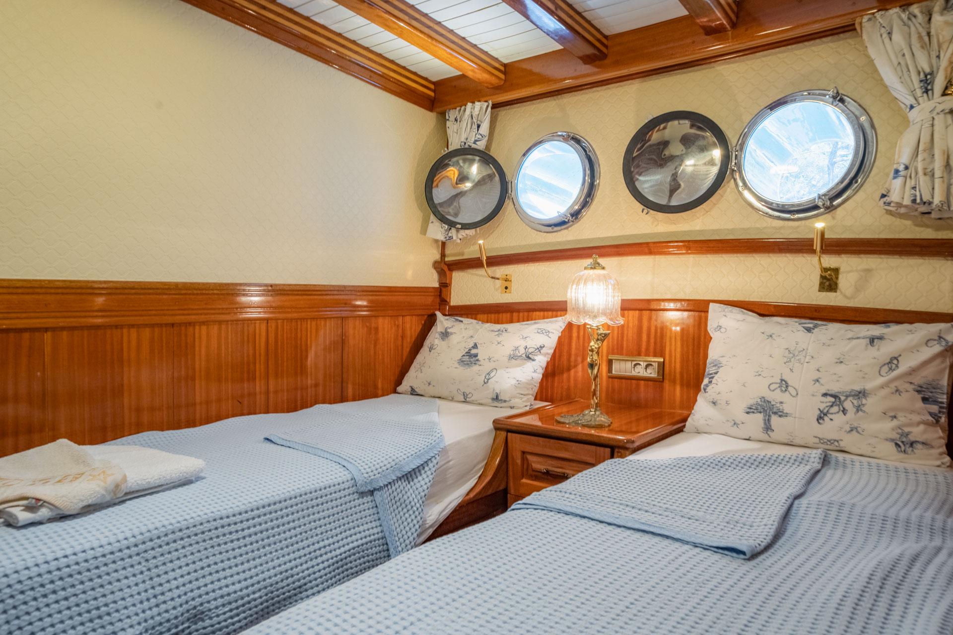 twin cabin interior with two single beds, nautical decor and four portholes