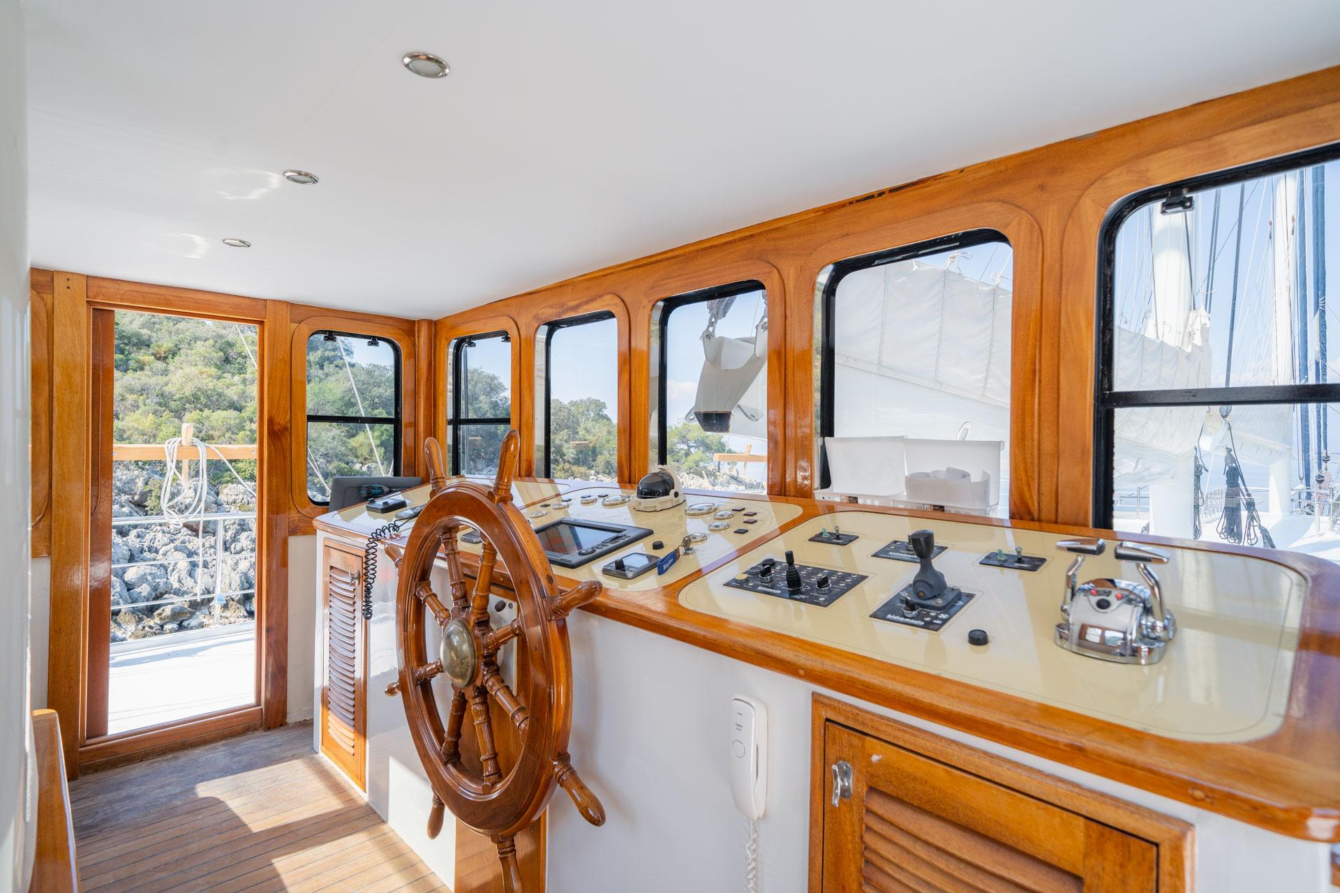 yacht wheelhouse interior showing wooden helm wheel and navigation control panel with instruments