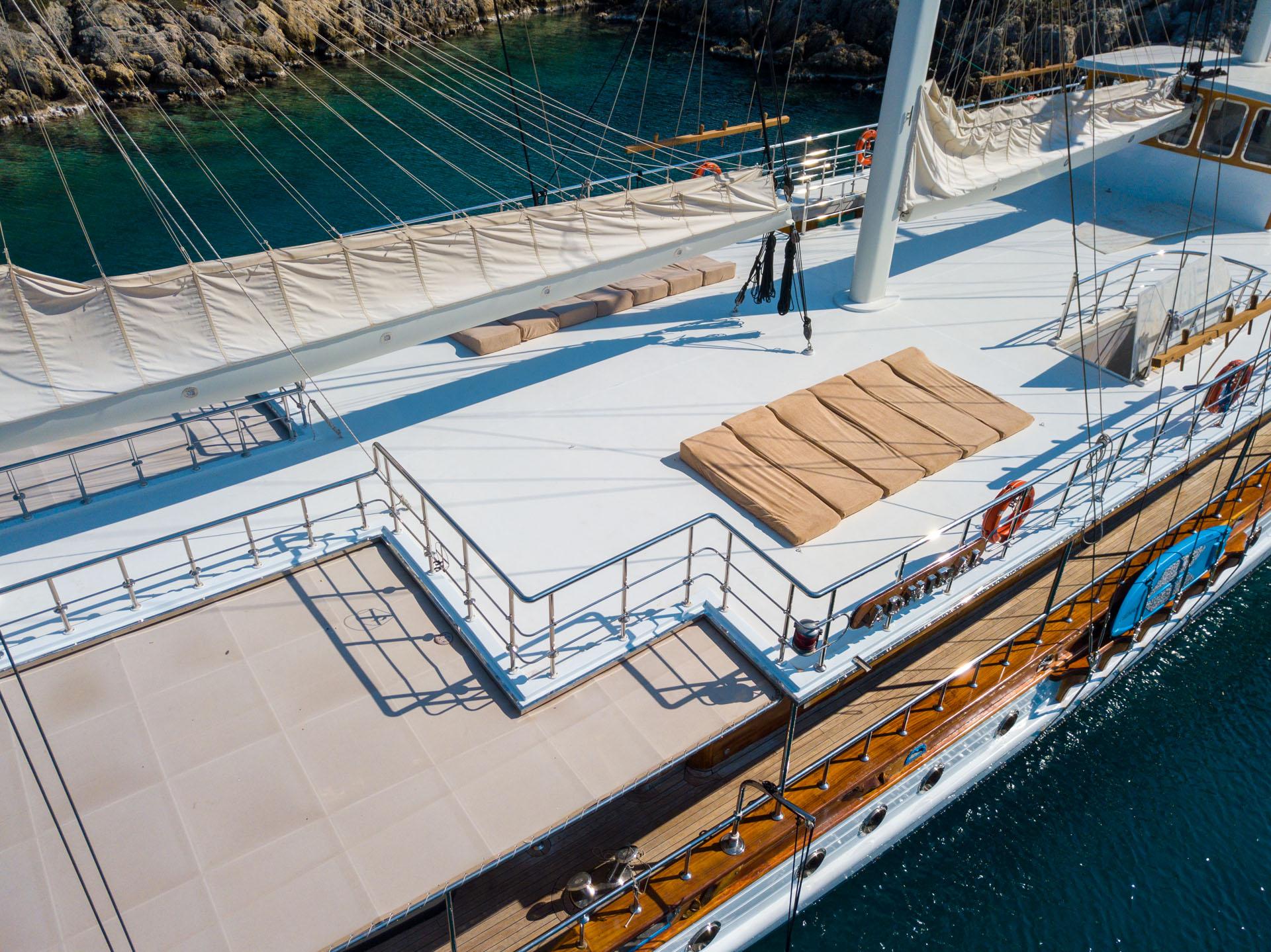 gulet upper deck with tan sun loungers, white railings and sailing rigging