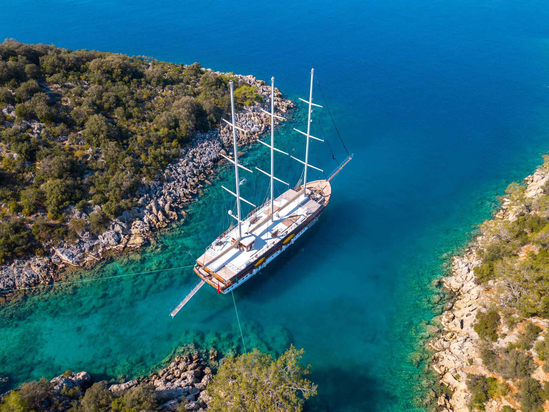 aerial view of traditional gulet yacht anchored in crystal clear turquoise bay