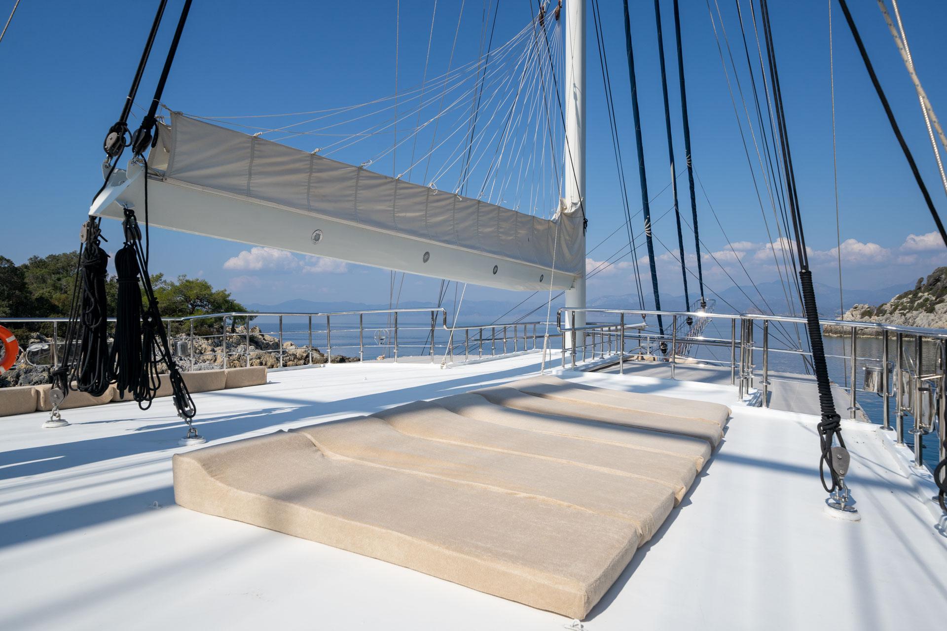 bow deck with beige cushioned sunbathing platform and white mast rigging
