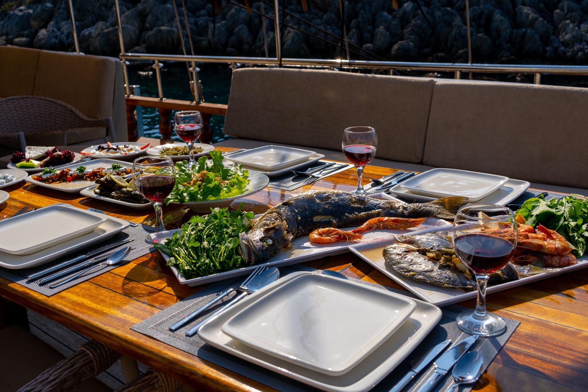 outdoor dining table with grilled seafood platter, fresh salads, and red wine glasses