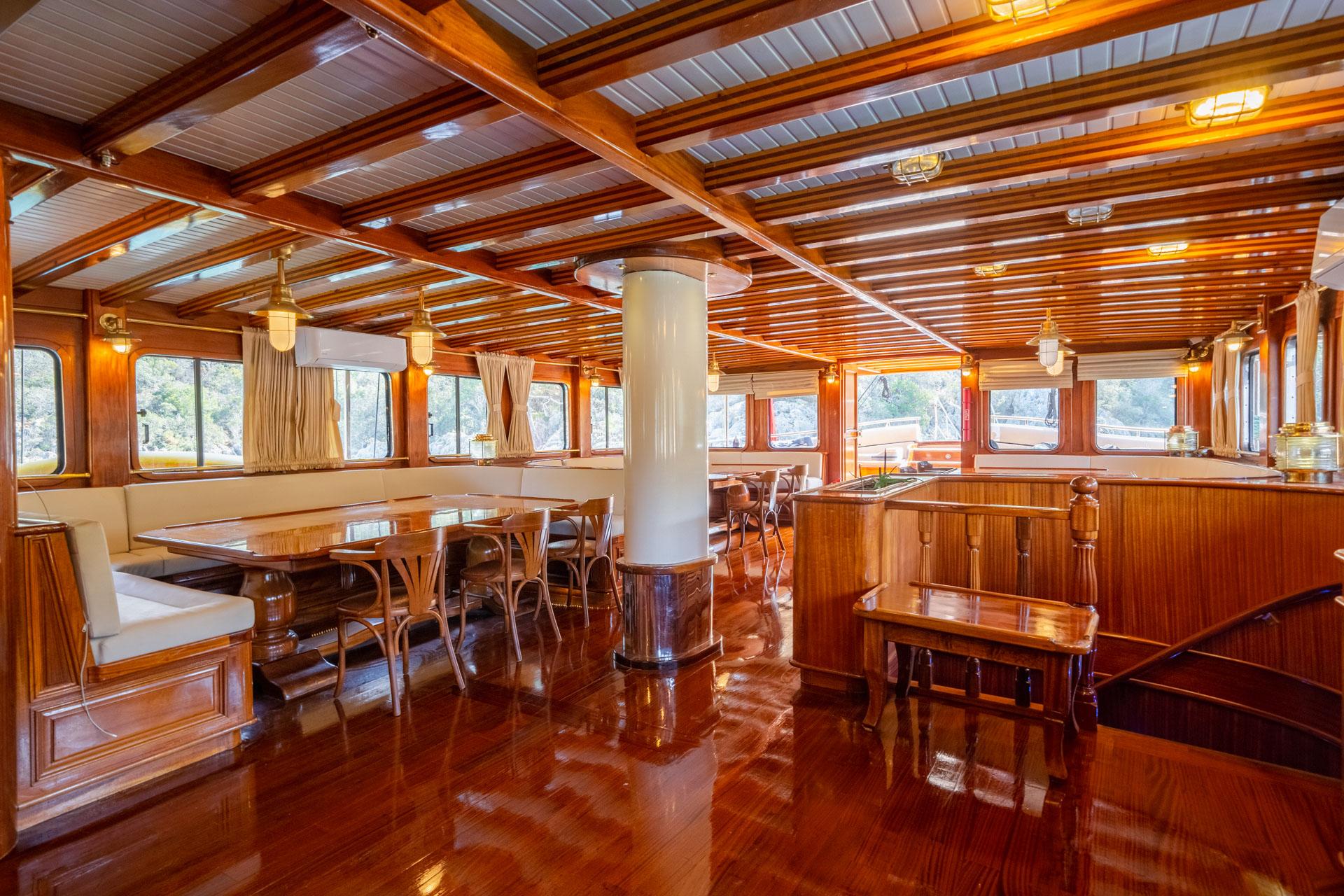 yacht interior salon with dining table, bentwood chairs, galley kitchen and wood paneling