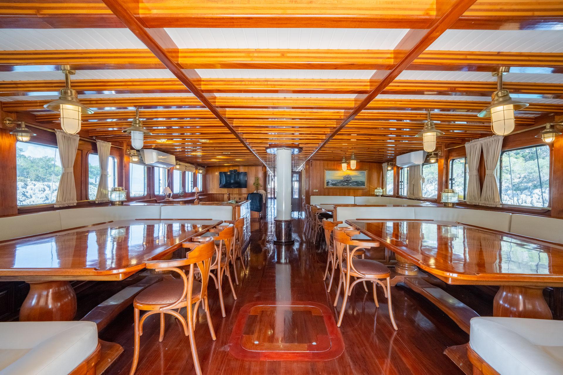 gulet interior dining salon with polished wooden tables, bentwood chairs, and panoramic windows
