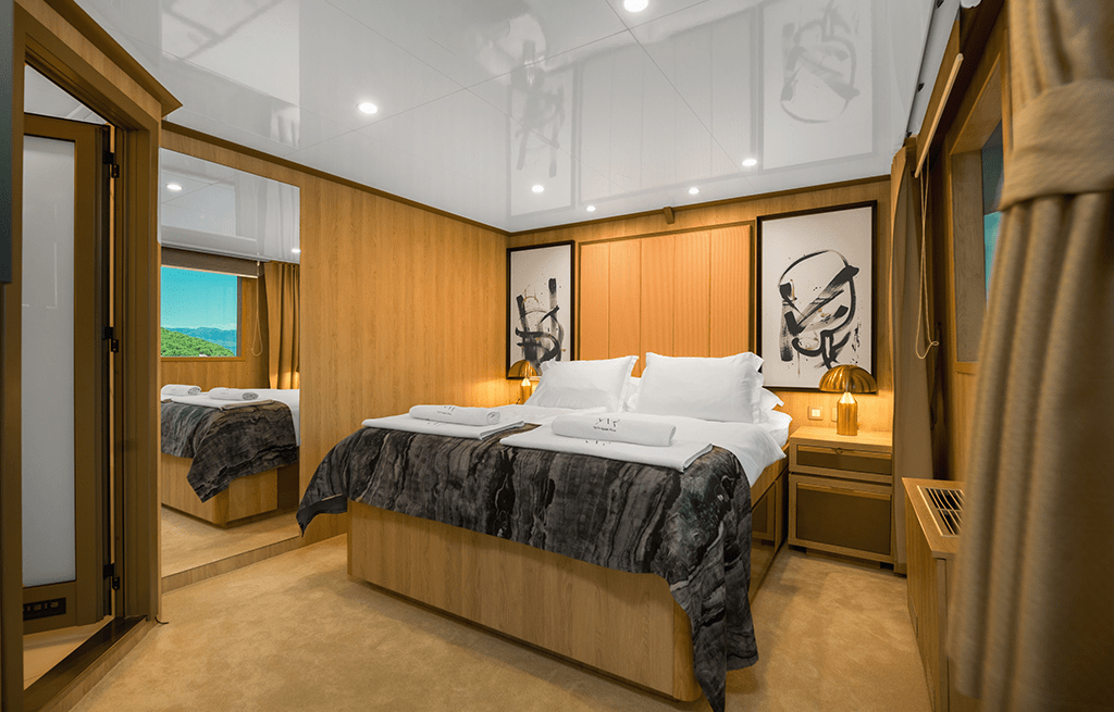 Luxury yacht master cabin with wooden paneling, double bed, and ensuite access