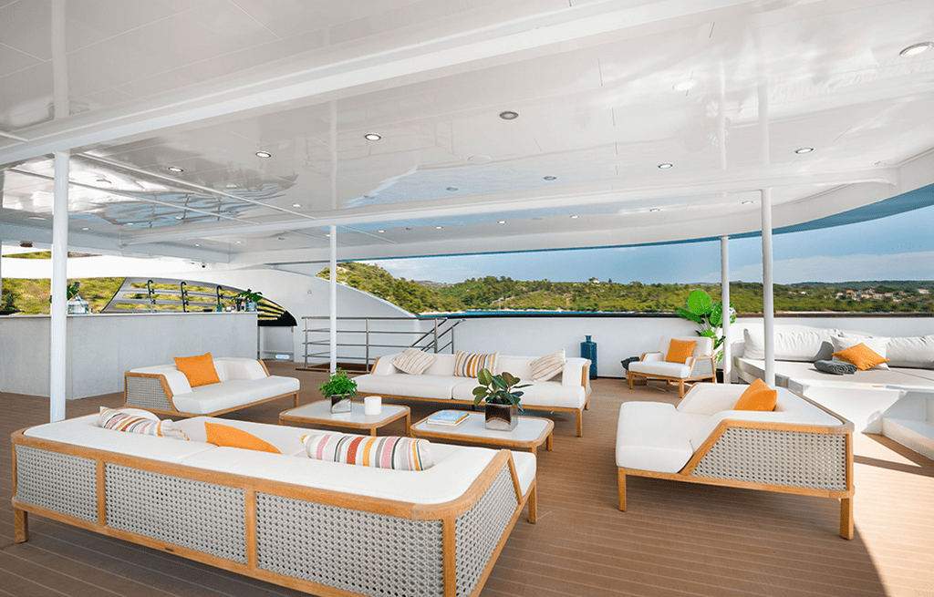 Luxury yacht upper deck lounge with white furniture and striped pillows