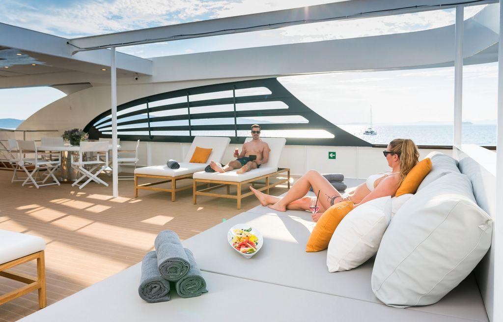 luxury yacht upper deck with white daybeds, canvas shade covering and ocean views