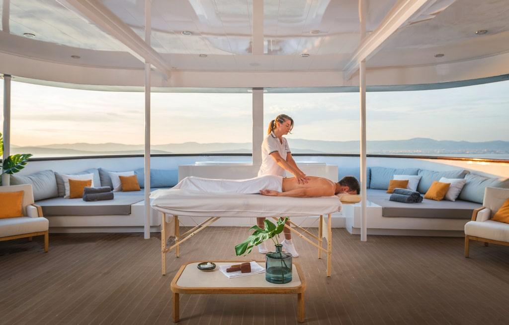 luxury yacht spa deck with massage therapist treating client under canopy