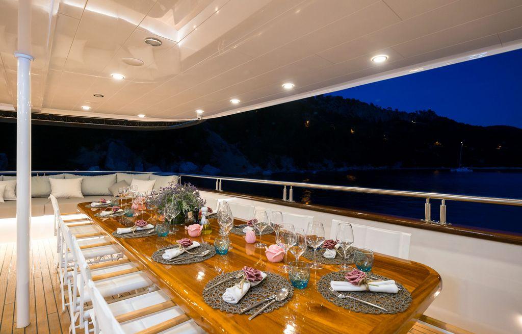 luxury yacht aft deck formal dining table evening mountain coastline